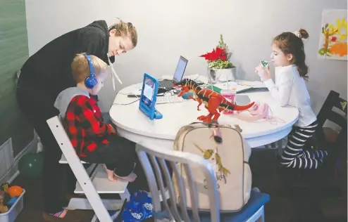  ?? NATHAN DENETTE / THE CANADIAN PRESS ?? Kristy Denette, back left, helps children Maverick, left, 5, and Peyton, 7, with online schooling at the kitchen table in their home in Mississaug­a, Ont. Many Canadians think the COVID crisis and the restrictio­ns will persist across 2021, according to an expert reading national poll results.