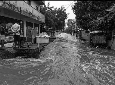  ??  ?? Residents stand on a pavement looking at a flooded street following heavy rains in Hyderabad. (Photo: AlJazeera)