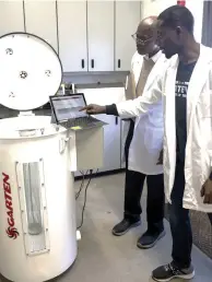  ?? (Special to The Commercial/University of Arkansas System Division of Agricultur­e) ?? Griffiths Atungulu (left), director of the Rice Processing Program, works with Samuel Olaoni, a Ph.D. student, on a miniature grain bin to test carbon dioxide sensors for monitoring grain quality.