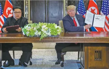 ?? EVAN VUCCI/ASSOCIATED PRESS ?? President Donald Trump holds up the document that he and North Korea leader Kim Jong Un had just signed Tuesday at the Capella resort on Singapore’s Sentosa Island. The statement, which U.S. officials had hoped would be a road map to a nuclear deal,...