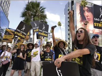  ?? CHRIS PIZZELLO — THE ASSOCIATED PRESS ?? SAG-AFTRA member John Schmitt, second from right, and others picket outside Netflix on Wednesday in Los Angeles. After the writers' strike ended, the actors strike continues in their bid to get better pay and working conditions.