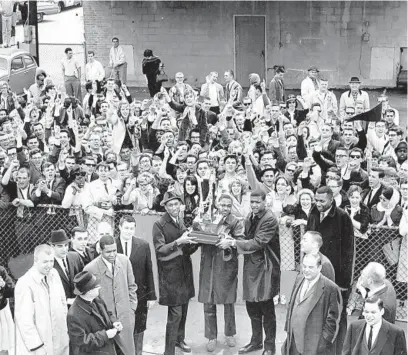  ??  ?? Fans give a rousing welcome to members of Loyola’s basketball team at O’Hare Internatio­nal Airport on their arrival from Louisville, Ky., circa March 25, 1963. Holding the national collegiate tournament trophy are, from left, Vic Rouse, Jerry Harkness and Les Hunter.