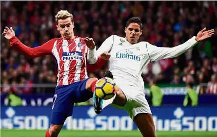  ?? — AFP ?? Best foot forward: Atletico Madrid’s Antoine Griezmann (left) vying with Real Madrid’s Raphael Varane during the La Liga match on Saturday.