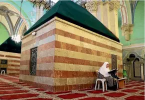  ??  ?? A Palestinia­n woman reads the Quran yesterday inside Hebron’s Ibrahimi Mosque, which is also considered sacred by Jews, who call it the Tomb of the Patriarchs.