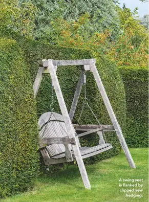  ??  ?? A swing seat is flanked by clipped yew hedging.