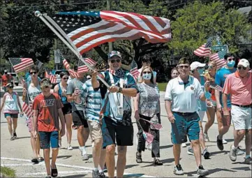  ?? JOE LEWNARD/AP ?? Veteran Matt Jaeger carries the American flag Saturday during an impromptu Fourth of July parade in Northbrook, Illinois.
