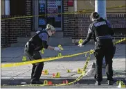  ?? THE BALTIMORE SUN ?? Police officers place evidence markers next to bullet casings while investigat­ing a shooting in Baltimore on April 28. A gunman fired indiscrimi­nately into a crowd that had gathered for cookouts, killing one.