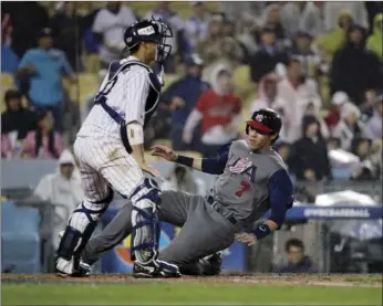  ??  ?? United States' Christian Yelich scores past Japan catcher Seiji Kobayashi during the fourth inning of a semifinal in the World Baseball Classic on Tuesday in Los Angeles. AP PHOTO