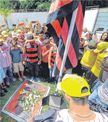  ?? PHOTO: CARL DE SOUZA/GETTY ?? Tragedy: Fans gather to lay flowers at the entrance of the Flamengo training centre after the fire in Rio de Janeiro, Brazil.