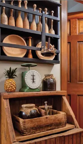  ??  ?? Left: An antique firewood box gets new life in a first-floor hallway of Darlene Sonnheim’s home. She covered the opening with a board and accented it with a rustic box, a green scale, and a collection of mashers on a black-painted plate rack. Cheeseclot­htopped crocks add country charm. Darlene says she uses rubber bands to keep the fabric tight before securing it with string.