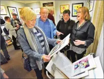  ?? Dan Watson/The Signal (See additional photos at signalscv.com) ?? Kathy Swaine, above left, examines watercolor­s by artist Meressa Naftulin, right, at the “Fresh Perspectiv­es” art exhibit presented by the Santa Clarita Artists Associatio­n in the newly remodeled art gallery in Newhall on Friday evening. At right, attendees examine art on display as part of Friday’s grand reopening event at the SCAA gallery.