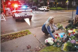  ?? MICHAEL HENNINGER / THE NEW YORK TIMES ?? Adrienne Wager, left, and Shannon Haldeman place f lowers Sunday in Pittsburgh near the Tree of Life Congregati­on, a day after 11 people died at the synagogue during a shooting rampage. The attack is part of a wave of anti-semitic attacks across the country and around the world.