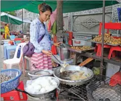  ?? PHA LINA ?? A woman cooks food at her streetside stall in central Phnom Penh last year.