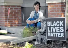  ?? Eric Lutzens, The Denver Post ?? Heather Luehrs sits on her front step near one of two signs in front of her home in the Lowry neighborho­od in Denver.