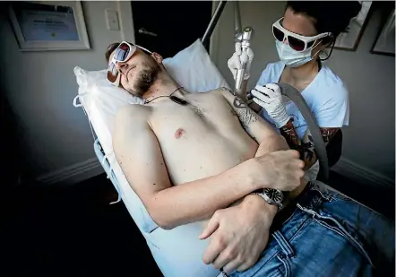  ?? PHOTO: LAWRENCE SMITH / FAIRFAX NZ ?? Don Rowe goes under Briar Neville’s laser at the Sacred Tattoo studio in Auckland.