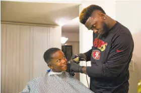  ??  ?? Mackey gives his son, Jamahl Jr., a haircut at their new home in Sacramento.