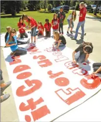  ?? Associated Press ?? Kountze High School cheerleade­rs and other children work on a large sign Wednesday in Kountze, Texas. The small Hardin County community is rallying behind the high school’s cheerleade­rs after the squad members were told they could not use scripture...