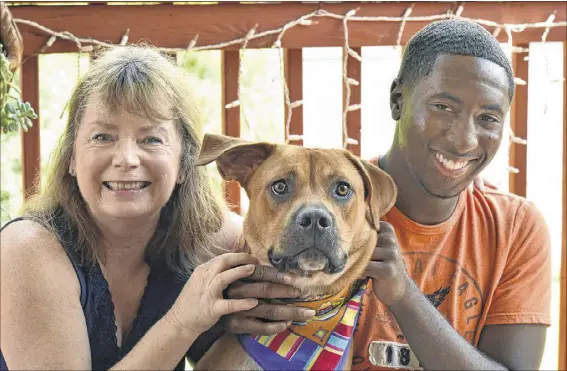  ?? HYOSUB SHIN PHOTOS / HSHIN@AJC.COM ?? Vicki Van Der Hoek and Leon Shields strike a pose with Vicki’s dog, Bobby, at her home in Morrow. The two met by chance 13 years ago when Vicki was down and out and Leon was a precocious little boy who always wanted a dog like her Lucky.