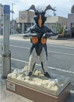  ?? Yomiuri Shimbun photos ?? Clockwise from top: A monument depicting Zetton stands on Taimatsu Street in Sukagawa, Fukushima Prefecture; The first Ultraman does a pose of firing a Specium Beam; Money-eating monster Kanegon sits on a bench.