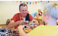  ?? FOTO: UWE MISERIUS ?? Kursleiter Jan Heinrichs zeigte den Kindern, wie man aus alten Getränkeka­rtons Piratenboo­te bauen kann.