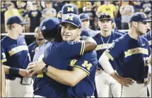  ??  ?? In this June 26, 2019 file photo, Michigan coach Erik Bakich, (center), is hugged by Michigan’s Ako Thomas (4) as they watch Vanderbilt celebrate after Vanderbilt defeated Michigan to win Game 3 of the NCAA College
World Series baseball finals in Omaha, Nebraska. (AP)