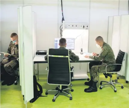 ??  ?? Soldaten bei Büroarbeit­en im temporären Corona-Behandlung­szentrum auf dem Berliner Messegelän­de.