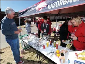  ?? NWA Democrat-Gazette/ANDY SHUPE ?? Donny Story (left), president and chief executive officer for Arvest Bank in Fayettevil­le, speaks to visitors at the Arvest tailgate March 5 before the Hogs’ 10-8 12-inning loss at Baum Stadium in Fayettevil­le.