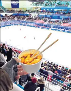  ?? ANDREW KEH/THE NEW YORK TIMES ?? Eating spicy rice cakes, or a popular street food in South Korea, while watching the joint Korean women’s hockey team play in Gangneung, South Korea, on February 14.