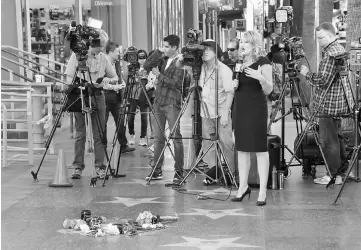  ??  ?? Members of the news media gather at Reynolds’ star along the Hollywood Walk of Fame in Los Angeles, on Thursday. — Reuters photo