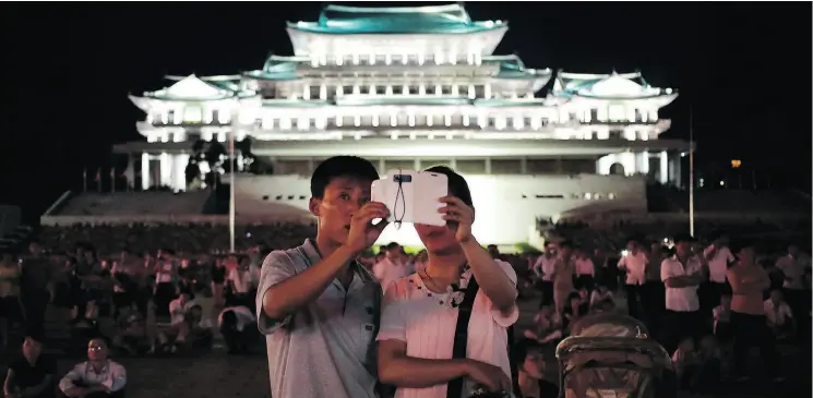  ?? WONG MAYE-E / THE ASSOCIATED PRESS FILES ?? A North Korean couple use their locally made smartphone to photograph fireworks. The regime is banking on an easing of U.S. sanctions to spur modernizat­ion plans.