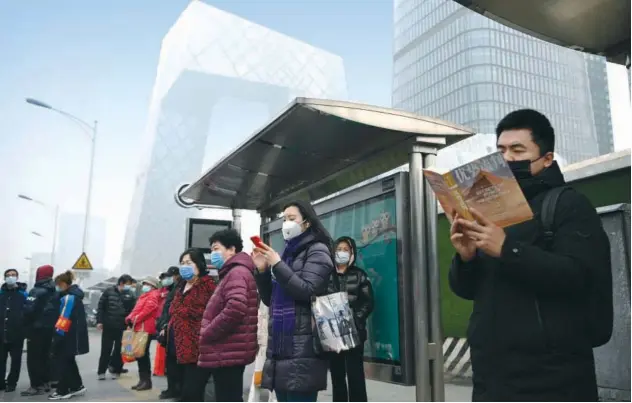  ?? Agence France-presse ?? ↑
Commuters at a bus stop in Beijing as China’s leaders work towards economic recovery on Friday.