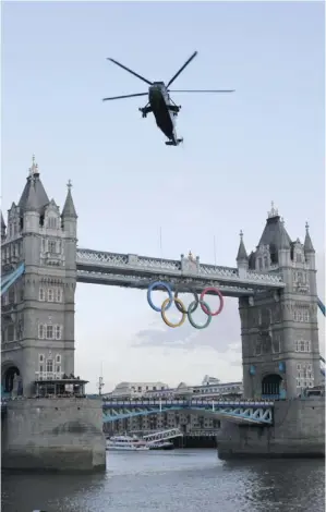  ?? LEFTERIS PITARAKIS / ASSOCIATED PRESS ?? A British Royal Marine Sea King helicopter carrying the Olympic flame flies past the
Tower Bridge in London, as it arrives at the Tower of London Friday.