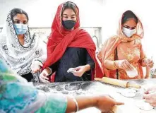  ??  ?? Ritu Singh, from left, Khushi Singh and Gunreet Singh prepare bhatura, a fried bread, at Sikh Center.