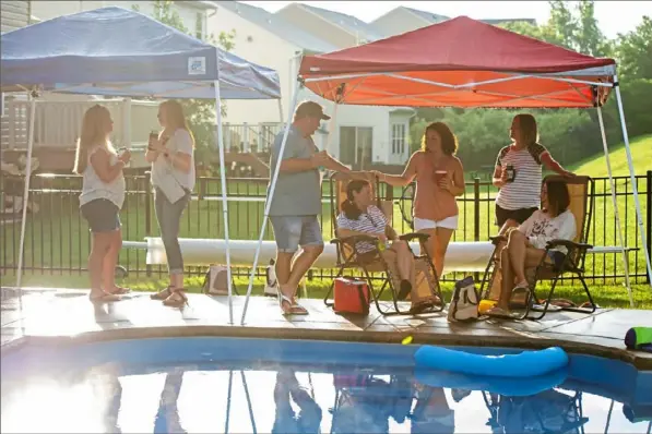  ?? Ben Braun/Post-Gazette ?? Guests stand and sit poolside during the Bellinger family’s Summer Porch Tour in Ohio Township.