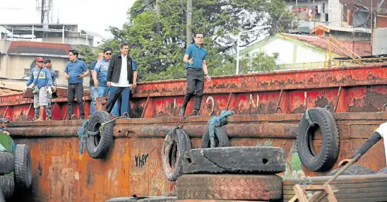  ?? —JOAN BONDOC ?? WATERWAY CLEARING OPERATION
RIVER WATCH Manila Mayor Francisco “Isko Moreno” Domagoso (right) checks a rusting barge on the Pasig River on Tuesday.