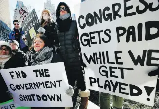  ??  ?? U.S. federal workers and their supporters hold signs during a protest in Boston on Friday.