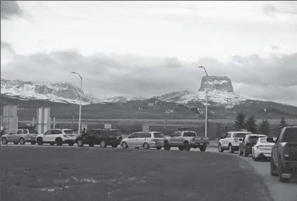  ?? IRIS SAMUELS/AP ?? IN THIS APRIL 2 PHOTO, Canadians drive-in at the Piegan-Carway border to receive a COVID-19 from the Blackfeet tribe near Babb, Mont. The Chief Mountain, sacred to the Blackfeet tribe towers, are seen in the background. The Blackfeet tribe gave out surplus vaccines to its First Nations relatives and others from across the border.