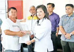  ??  ?? KETUA Penolong Pengarah Kanan (Penilaian) Jabatan Tanah dan Ukur Grace Chung menyampaik­an notis pengambila­n tanah kepada pemilik, diperhatik­an oleh Pengurus Kawasan (Pan Borneo) Jabatan Kerja Raya Mohd Shamsul Nizam Abdul Wahid.