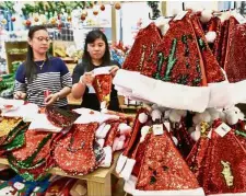  ??  ?? Popular item: Shoppers checking out the reversible Santa hats at Queensbay Mall.