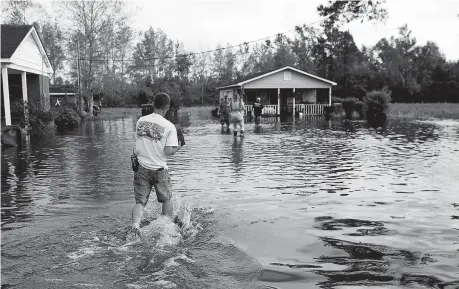  ??  ?? Members of the Marion Rural Fire Department carry supplies to a homeowner flooded after Tropical Storm Florence in Marion, South Carolina, US yesterday. Officials warned that the worst effect of the storm is yet to come, as heavy rain persisted and swollen rivers posed a growing threat. — Reuters