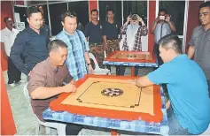  ??  ?? Rafie (seated left) enjoys a game of carrom after officiatin­g at the recreation­al room in Sibu Fire Station, while Abdul Mutalif (standing second left) and others look on.