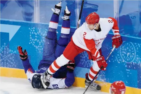  ?? KIRILL KUDRYAVTSE­V/ AFP/ Getty Images ?? Slovakia’s Tomas Syrovy, left, ends up in a dangerous position next to Russian Artyom Zub in men’s hockey Wednesday at the Gangneung Hockey Centre in Gangneung. Slovakia upset the Olympic Athletes from Russia 3- 2.