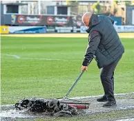  ??  ?? A groundsman tries to get Dens Park playable