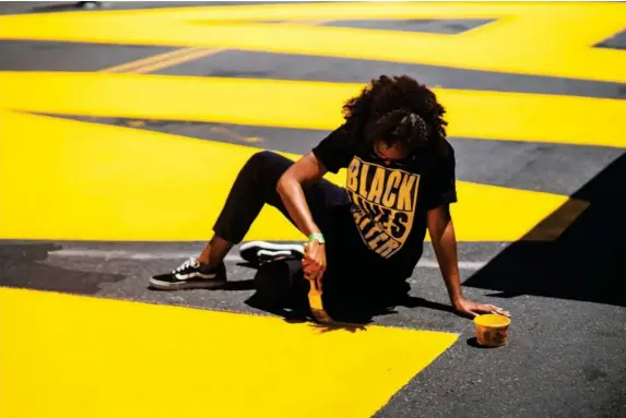  ?? (Reuters) ?? A woman paints a Black Lives Matter mural on a street in Brooklyn