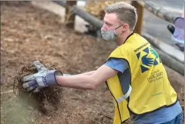  ?? Dan Watson/ The Signal ?? (Above) Chandler Neeley, 18, joins hundreds of volunteers as he helps spread the hundreds of yards of mulch during the Church of Jesus Christ of Latter-day Saints’ Day of Service beatificat­ion project at the Newhall Park and Ride on Saturday. (Left) Abby Jacobs, left, and Catherine Houghes use their hands to spread mulch during Saturday’s event.