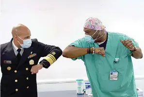  ?? Youngrae Kim/Chicago Tribune via AP, Pool ?? Surgeon General of the U.S. Jerome Adams, left, elbow-bumps Emergency Room technician Demetrius Mcalister after Mcalister got the Pfizer COVID-19 vaccinatio­n at Saint Anthony Hospital in Chicago, on Tuesday, Dec. 22, 2020.
