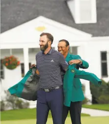  ?? Doug Mills / New York Times ?? Tiger Woods, who has five green jackets, helps Dustin Johnson put on his after Johnson picked up his second major title.