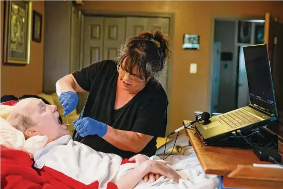  ?? Photos by Shafkat Anowar/Dallas Morning News ?? Rick Frame, 59, of Arlington, gets his teeth flossed by Angela Blankenshi­p, his personal care attendant. Frame has been paralyzed from the neck down since a motorcycle accident in 1999. Blankenshi­p is paid $9.75 an hour from Texas Medicaid funds that Frame receives for his care.