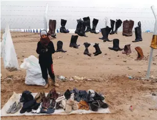  ?? (Ammar Awad/Reuters) ?? A DISPLACED boy who fled the Islamic State stronghold of Mosul sells second-hand shoes yesterday following heavy rain in Khazer, Iraq.