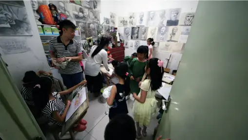  ??  ?? Teachers hold a children’s art class at a training school in Beijing, May 30, 2015